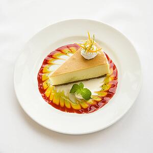 Gourmet slice of pie garnished with zest and sauce and mint sprig.