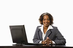 Businesswoman sitting at desk with computer smiling