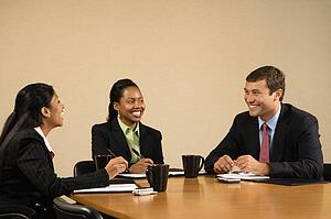 Businesspeople sitting at conference table talking and smiling