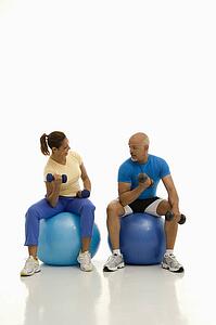Balancing on exercise balls while working out with dumbbells