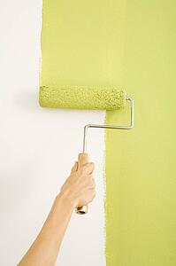 Female hand painting on wall with roller