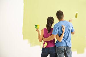Couple standing in front of partially painted wall