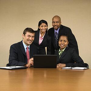Businesspeople gathered around laptop computer smiling