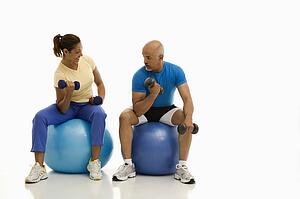 Balancing on exercise balls while working out with dumbbells