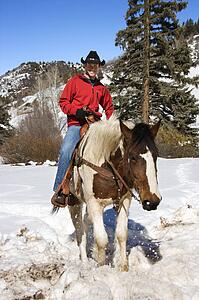 Man horseback riding in snowy mountains
