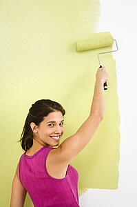 Woman painting interior wall of home with paint roller