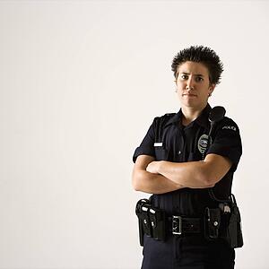Portrait of mid adult Caucasian policewoman standing with hand on gun holster looking at viewer.