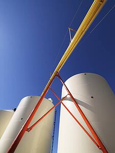 Low angle view of metal grain storage silos against blue background