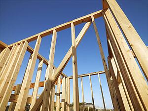 Low angle view of new construction framework for house with blue sky 