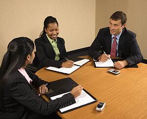 Businesspeople sitting at conference table talking and smiling.