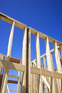 Wooden framework of new construction with blue sky in background.