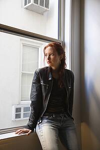 Woman sitting indoors on window ledge 