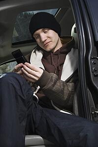 Caucasian male teenager text messaging with cellphone.