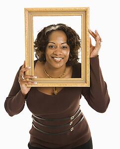 Woman holding empty frame around head smiling