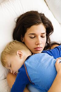 Woman with toddler son sleeping in bed 