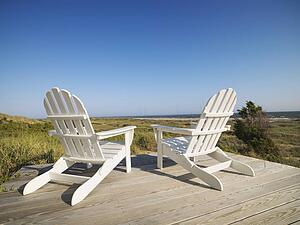 Two adirondack chairs on wooden deck overlooking beach at Bald Head Island, North Carolina.