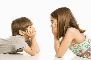 Portrait of girl and boy laying down looking at each other