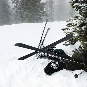Skiers lying in snow near tree after crash in fog