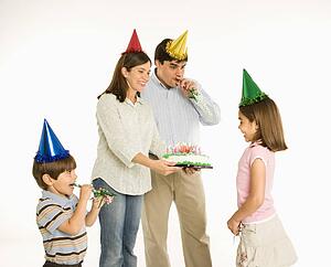 Family celebrating girl's birthday with cake.