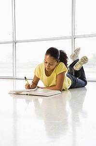 Girl lying on floor doing schoolwork