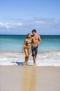 Couple embracing and smiling as they walk out of water in Maui, Hawaii