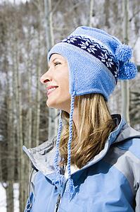 Side view head and shoulder of attractive smiling mid adult blond woman wearing blue ski clothing