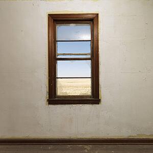 Empty abandoned room with window centered on wall