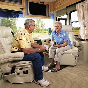 Senior couple sitting in RV holding coffee cups and smiling