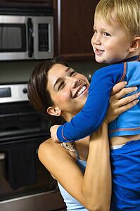 Woman in kitchen lifting son