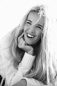 Black and white head and shoulder portrait of pretty blond Caucasian woman smiling and laughing.