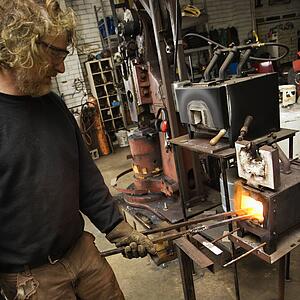 Metal-smith heating metal in forge