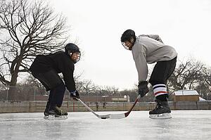 Two ice hockey player boys in uniform facing off on ice.