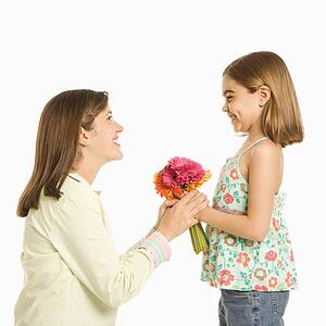 Girl giving bouquet of flowers to mother