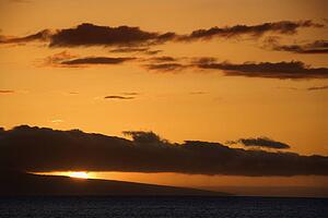 Orange sunset behind island in Pacific ocean
