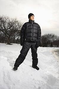 Teenage boy standing in snow wearing winter clothes.