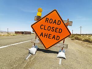 Road sign on rural highway warning that road is closed ahead.