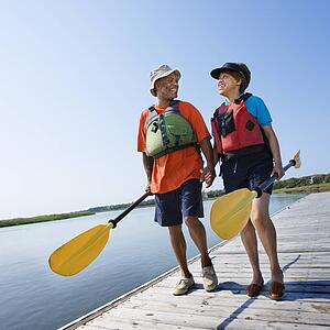 Couple walking dock carrying paddles