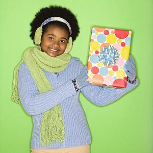 African American girl in winter clothing holding wrapped package.