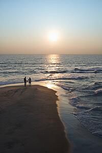 Aerial view of couple holding hands on beach in Bald Head Island, North Carolina at sunset.