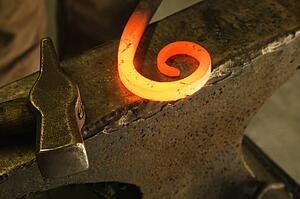 Hot shaped metal laying on anvil with hammer.