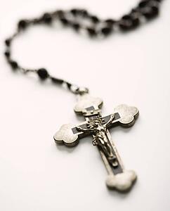 Christian rosary beads with crucifix on white background.