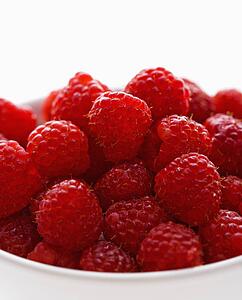 Bowl of raspberries against white background.