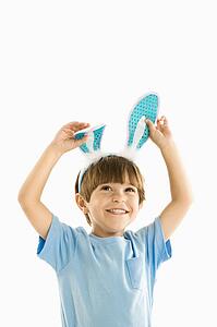 Portrait of boy wearing rabbit ears smiling.