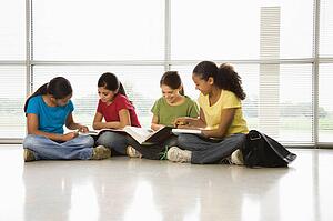 Girls sitting together on floor with schoolwork