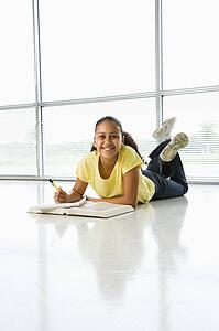 Girl lying on floor doing homework 