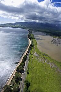 Aerial of road following Maui, Hawaii coastline with beach