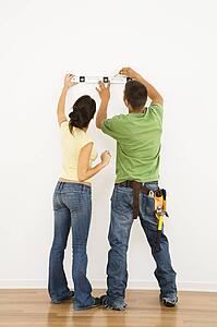 Couple holding level to wall 