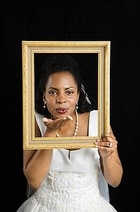 Bride holding frame around her face and blowing a kiss