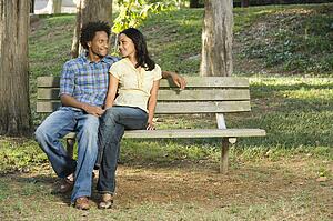 Smiling couple sitting on park bench 
