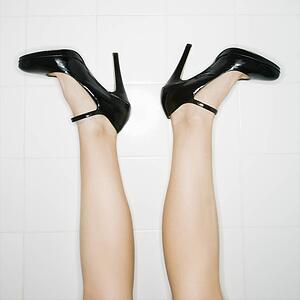 Caucasian female legs sticking up in air with high heels turned out.